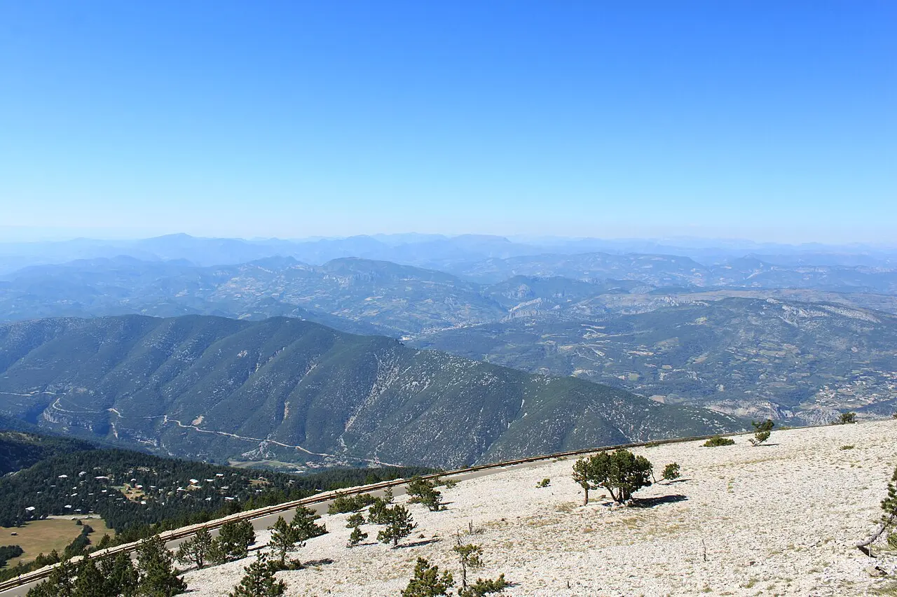 The sweeping view from the limestone summit of Mont Ventoux over the mountains and valleys of Provence, France, under a clear blue sky.