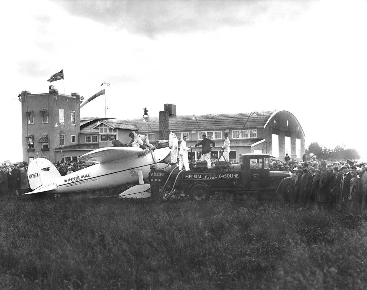 Wiley Post's Lockheed Vega, the Winnie Mae, being refueled at Edmonton, Alberta, during his 1933 solo flight around the world, with a crowd looking on
