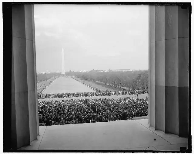 The crowd of about 75,000 people gathered on the National Mall before the Lincoln Memorial on April 9, 1939, seen through the memorial's columns, with the Washington Monument in the distance.