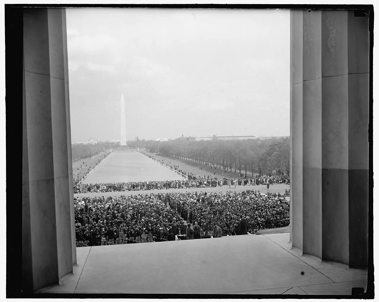 The crowd of about 75,000 people gathered on the National Mall before the Lincoln Memorial on April 9, 1939, seen through the memorial's columns, with the Washington Monument in the distance.
