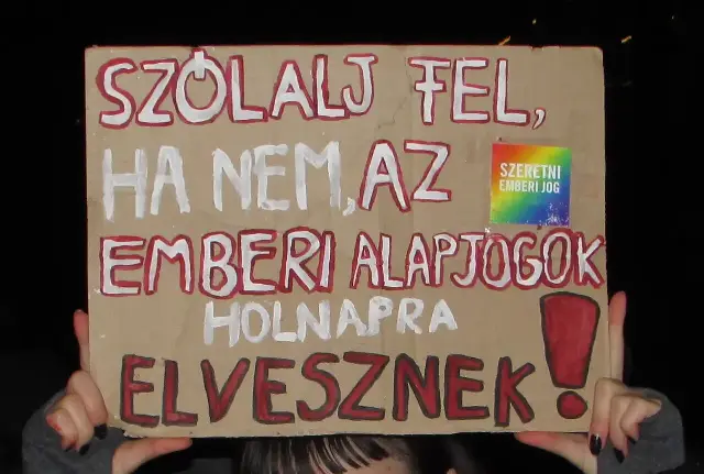 An Amnesty International supporter holds a handwritten human-rights sign at a modern forum (illustrative).