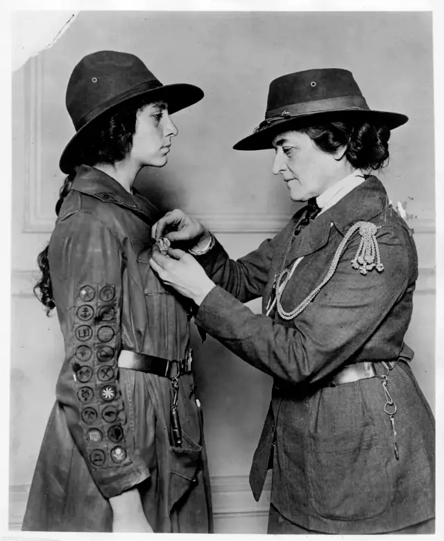Juliette Gordon Low pinning a badge on a uniformed Girl Scout