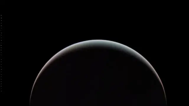 A thin crescent of Uranus glowing pale blue-green against black space, processed from Voyager 2 images taken during the 1986 flyby.