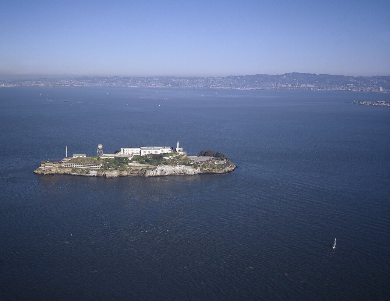 Aerial view of Alcatraz Island in San Francisco Bay, showing the prison buildings, lighthouse, and water tower.