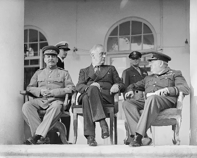 Joseph Stalin, Franklin D. Roosevelt, and Winston Churchill seated together on the portico of the Soviet embassy in Tehran in 1943 (period photograph).