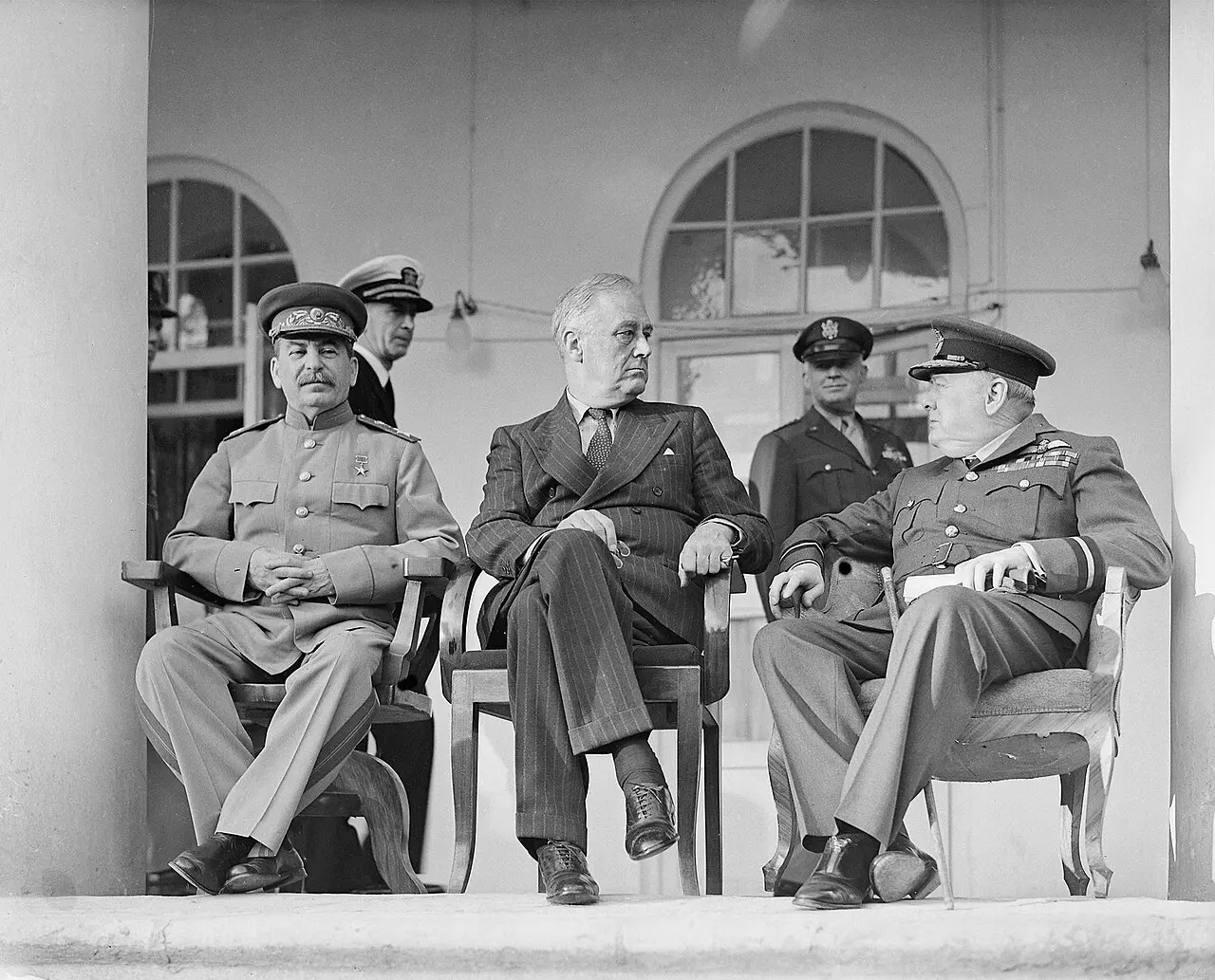 Joseph Stalin, Franklin D. Roosevelt, and Winston Churchill seated together on the portico of the Soviet embassy in Tehran in 1943 (period photograph).