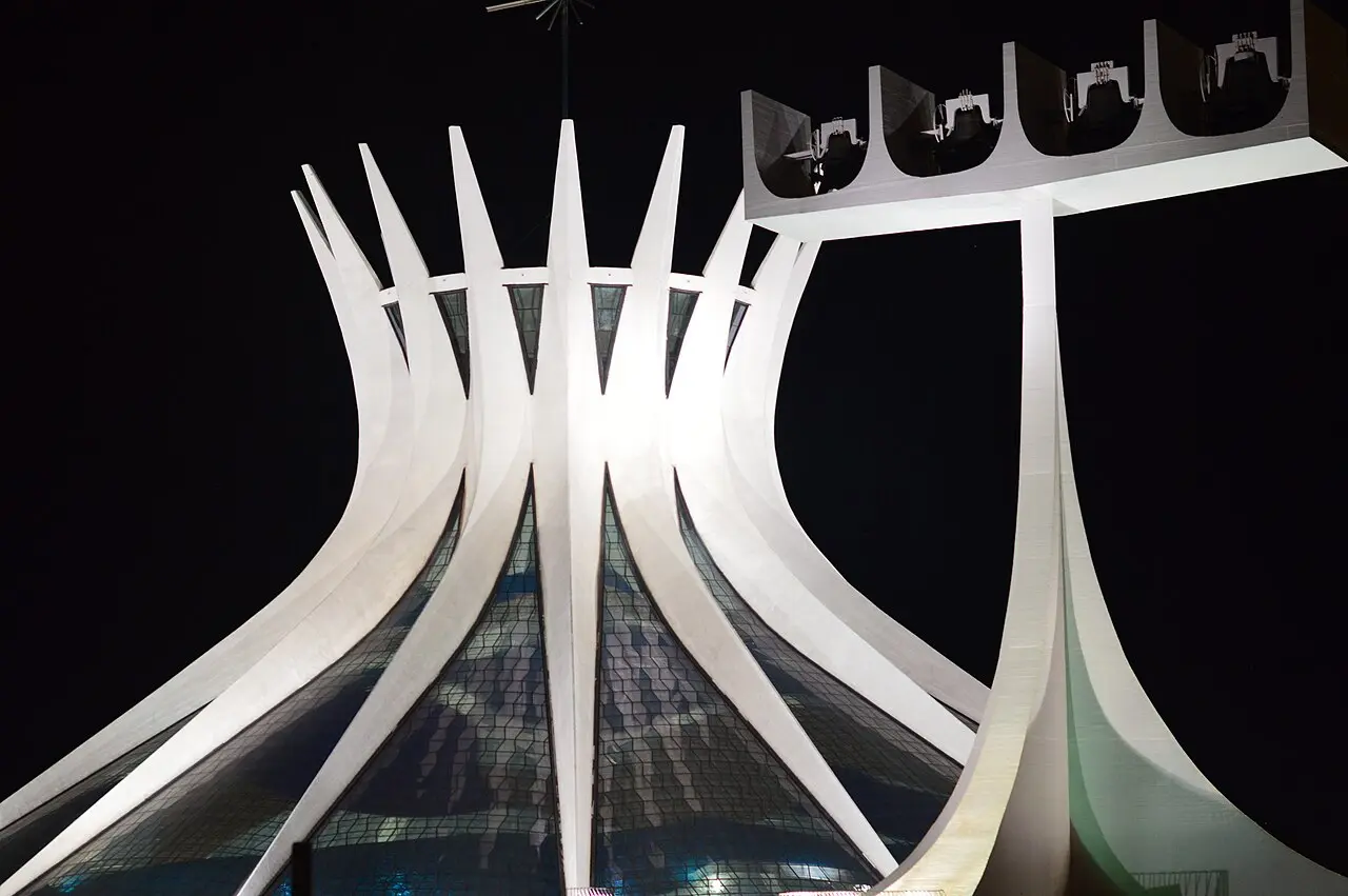 Oscar Niemeyer's Cathedral of Brasília, its concrete columns rising like hands toward the sky, photographed at night.