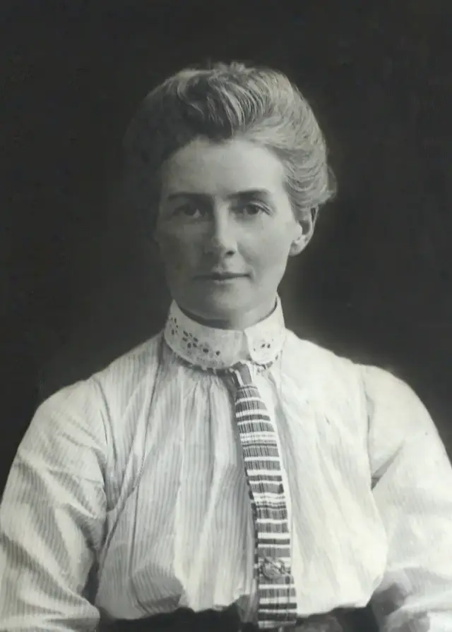 A formal black-and-white studio portrait of nurse Edith Cavell, wearing a dark dress with a white collar and a Red Cross-style nurse's veil.