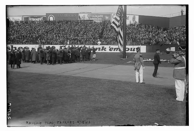 The flag-raising ceremony at Yankee Stadium's opening day, April 18, 1923, before a packed grandstand.