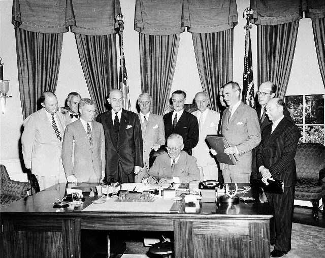 President Truman signs the document implementing the North Atlantic Treaty on August 24, 1949 — a later photograph from the treaty's first year; illustrative.