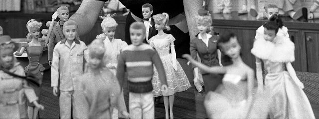 A group of early Barbie and Ken dolls from the first years of the line, photographed in black and white.