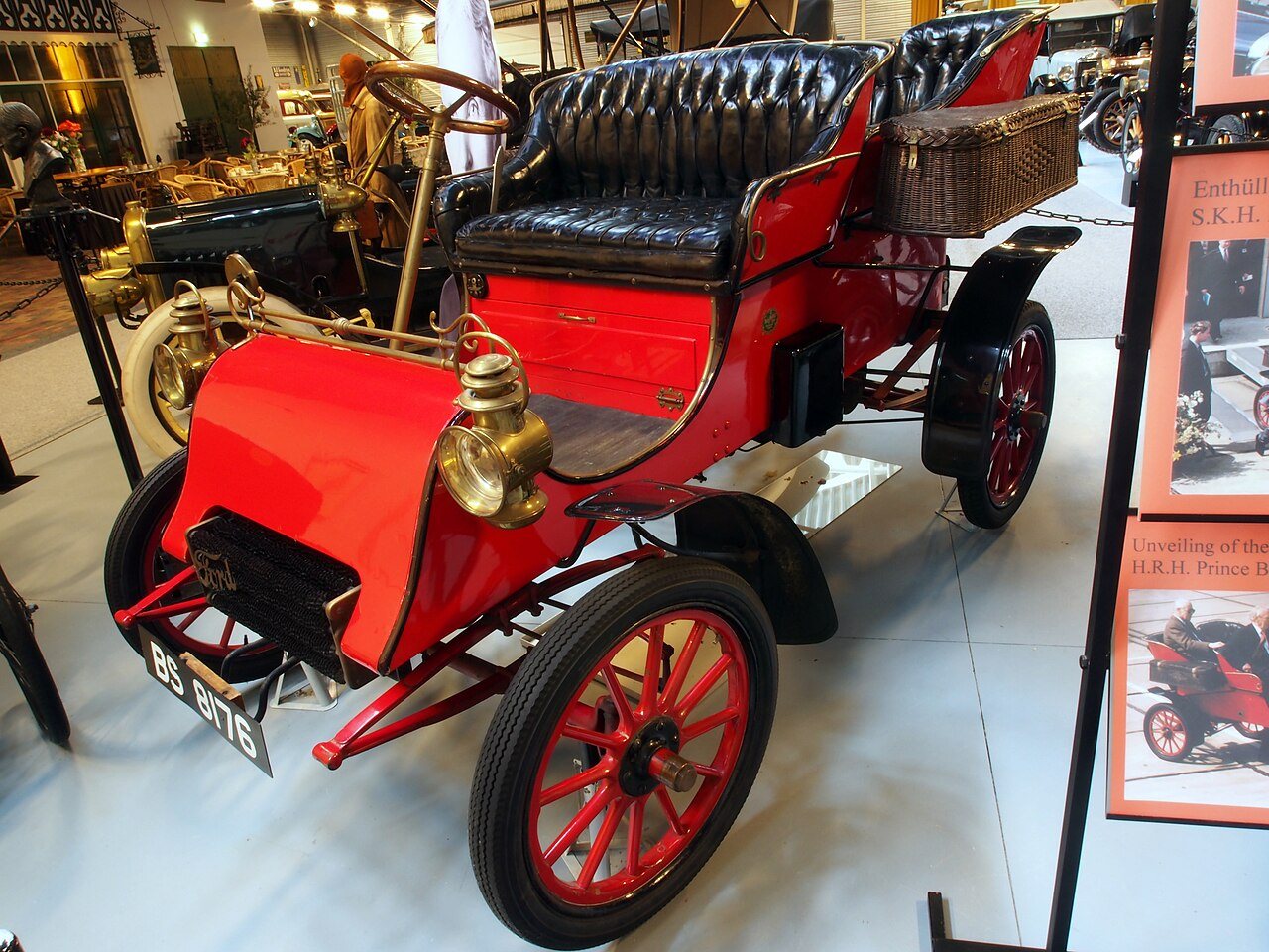 A surviving red 1903 Ford Model A on display in a museum, showing the open-topped two-cylinder car with brass headlamps
