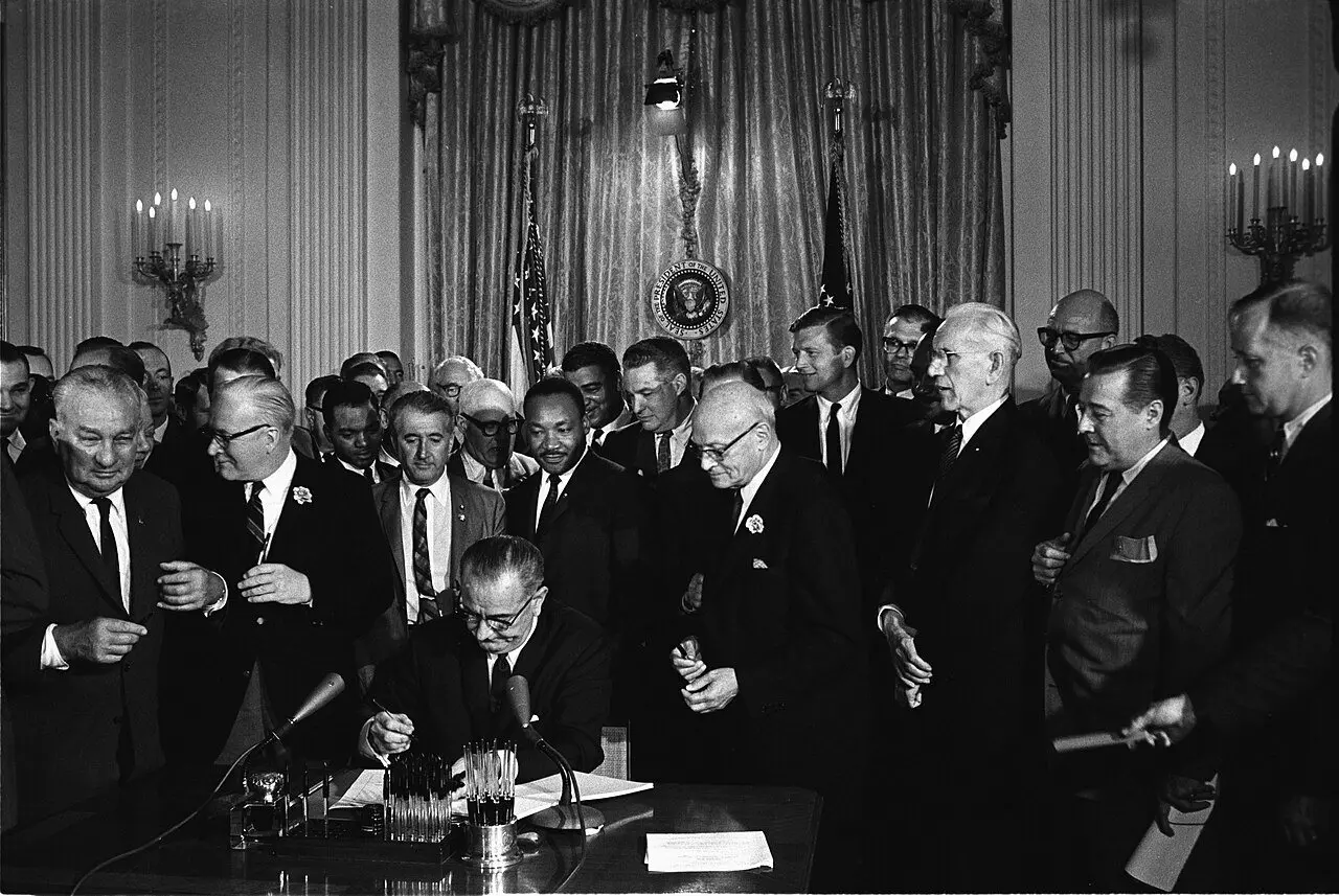 President Lyndon B. Johnson signs the Civil Rights Act of 1964 at the White House as Martin Luther King Jr. and others look on