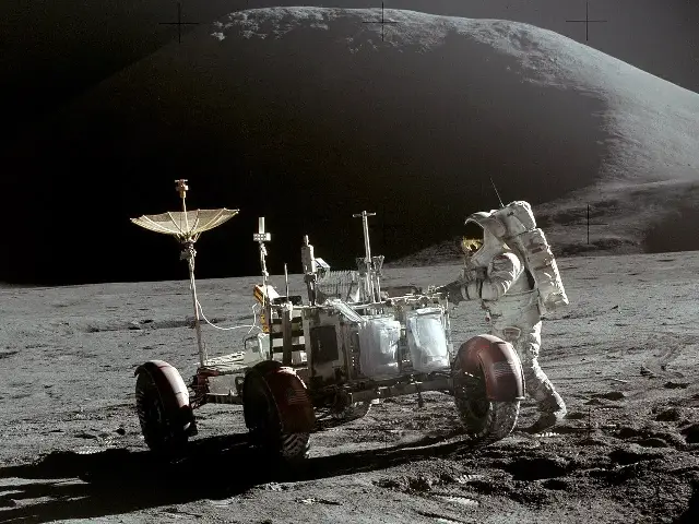 Astronaut Jim Irwin with the Lunar Roving Vehicle at the end of Apollo 15's first moonwalk, photographed by commander David Scott, with Mount Hadley behind.