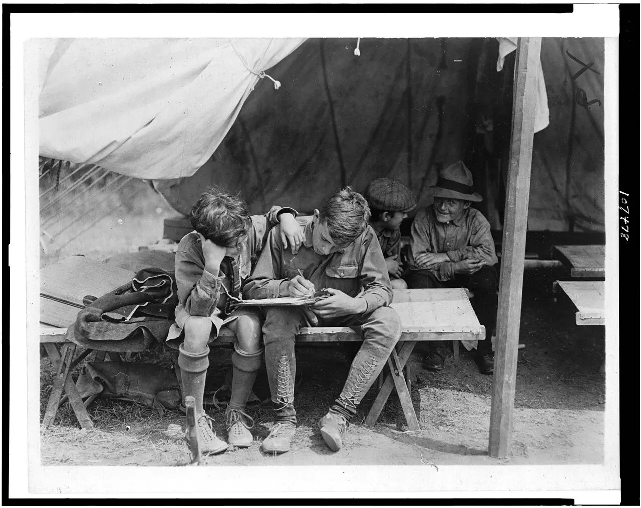 Four Boy Scouts at a 1912 camp on Hunter's Island write letters home from inside a tent