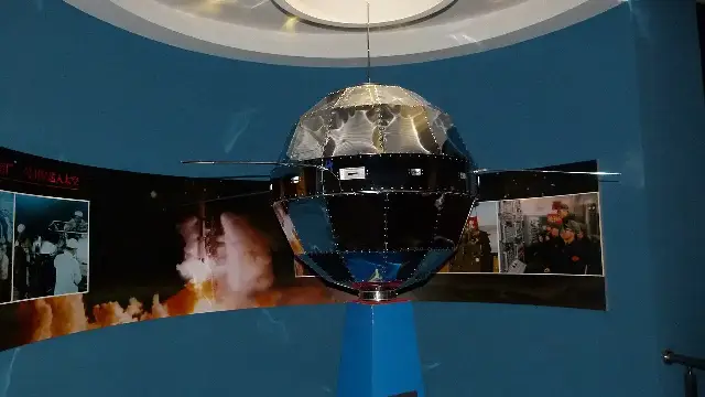 A museum model of the Dong Fang Hong 1 satellite: a faceted metal sphere about a meter across with four long whip antennas.