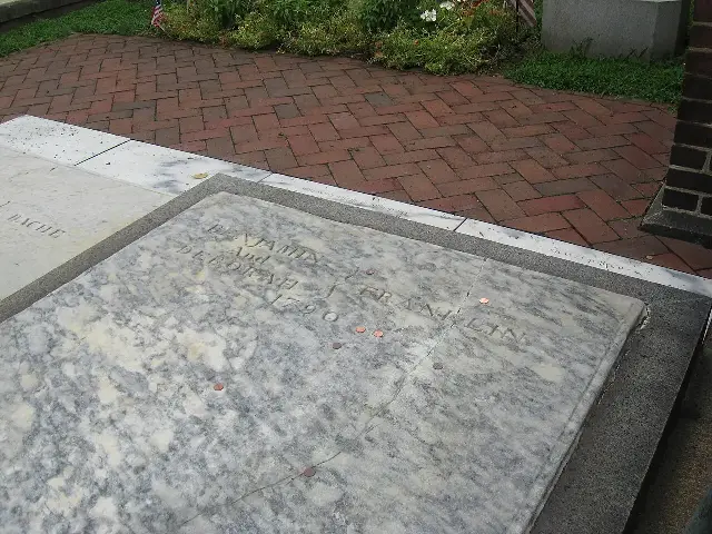 The marble grave slab of Benjamin and Deborah Franklin at Christ Church Burial Ground in Philadelphia, dotted with pennies left by visitors.