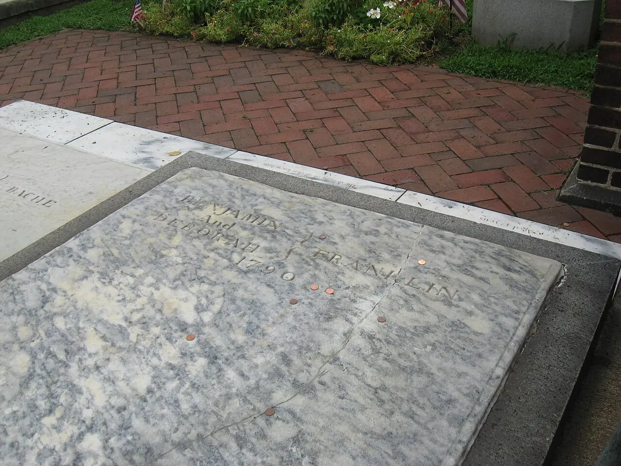The marble grave slab of Benjamin and Deborah Franklin at Christ Church Burial Ground in Philadelphia, dotted with pennies left by visitors.
