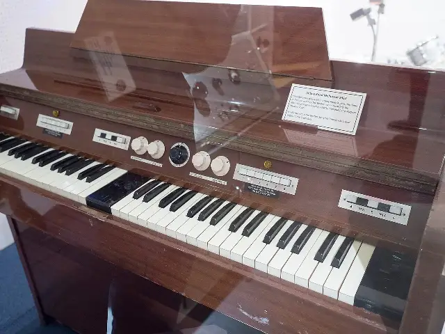 A wooden Mellotron Mk II keyboard with a museum placard explaining that the same model was used by the Beatles at Abbey Road Studios when recording Sgt. Pepper's Lonely Hearts Club Band in 1967.