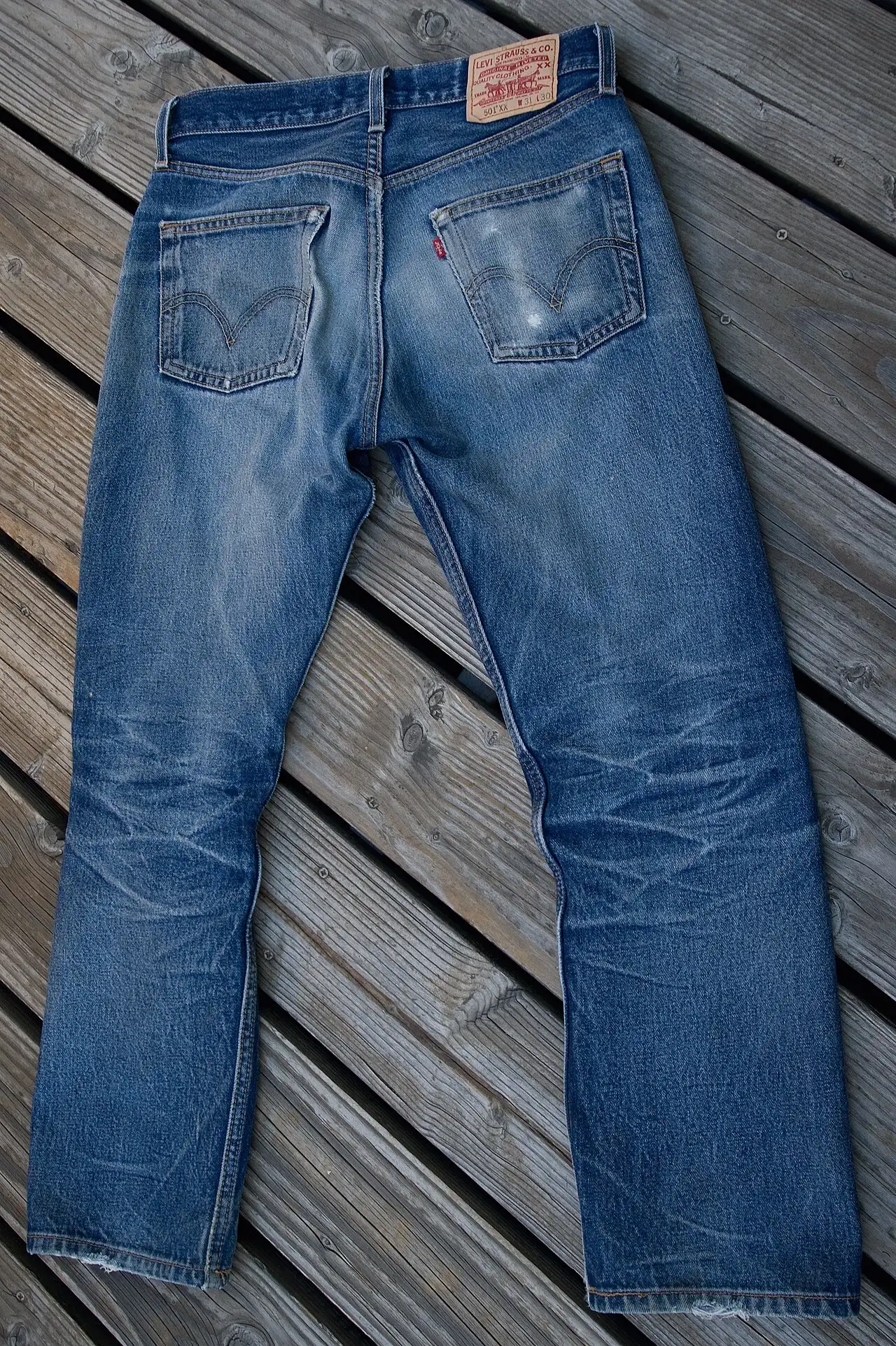 A pair of Levi's 501 blue jeans, the style born from the 1873 rivet patent, photographed from the back showing the leather patch and red tab.