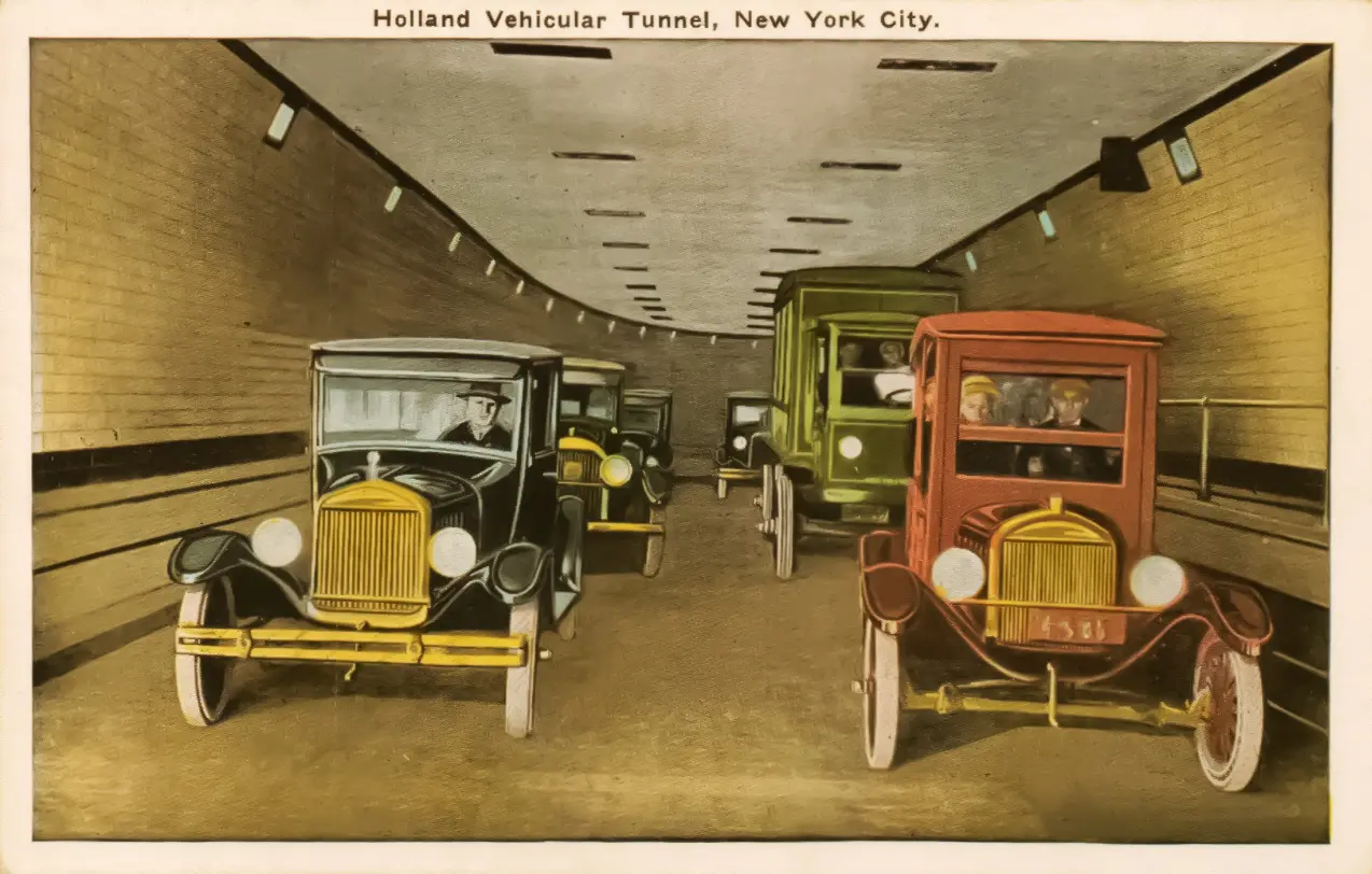 A 1927-era colorized postcard showing automobiles driving through the tiled interior of the Holland Tunnel under the Hudson River.