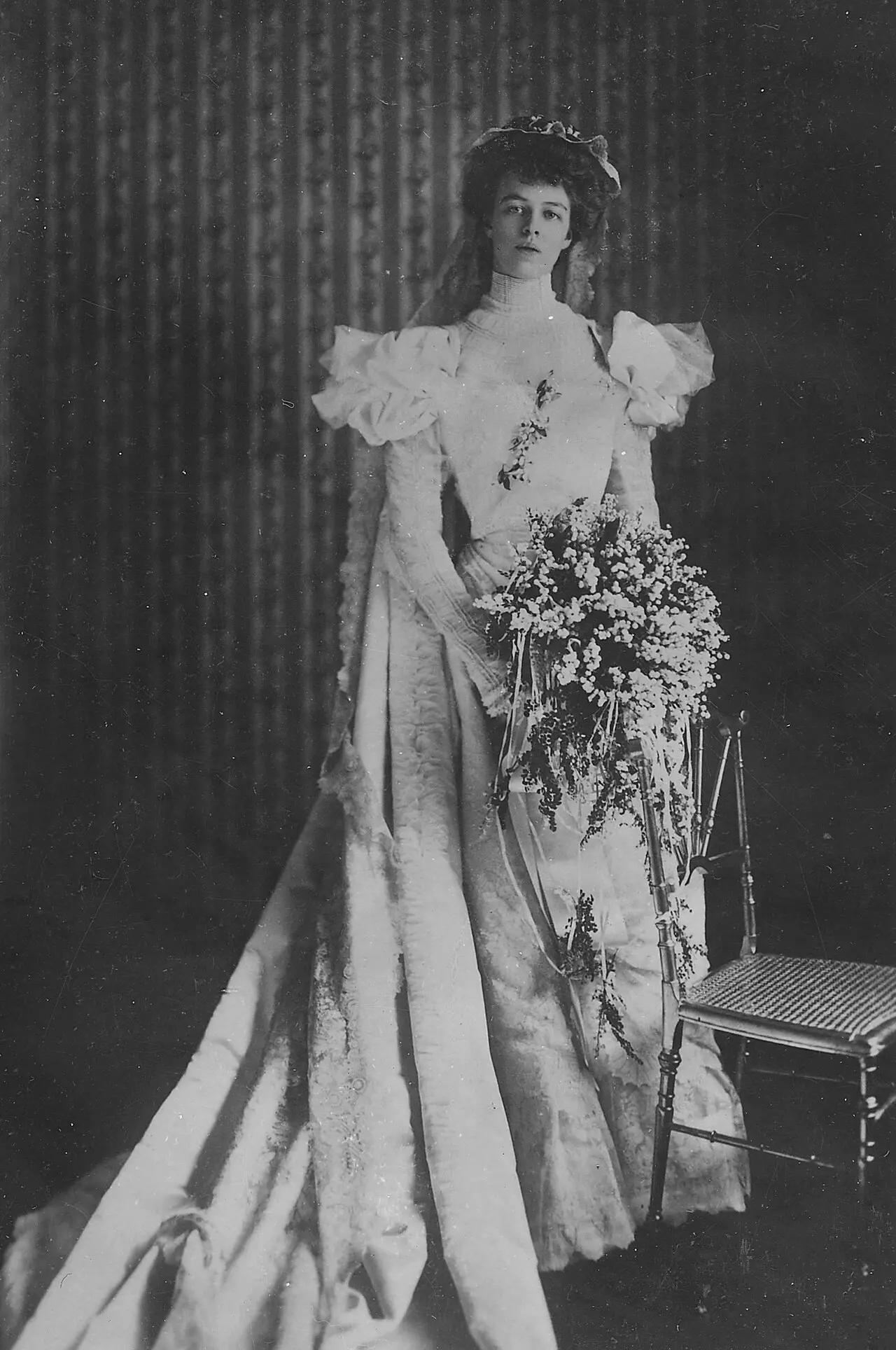 Eleanor Roosevelt in her 1905 white satin wedding dress, holding a large bouquet of lilies of the valley.