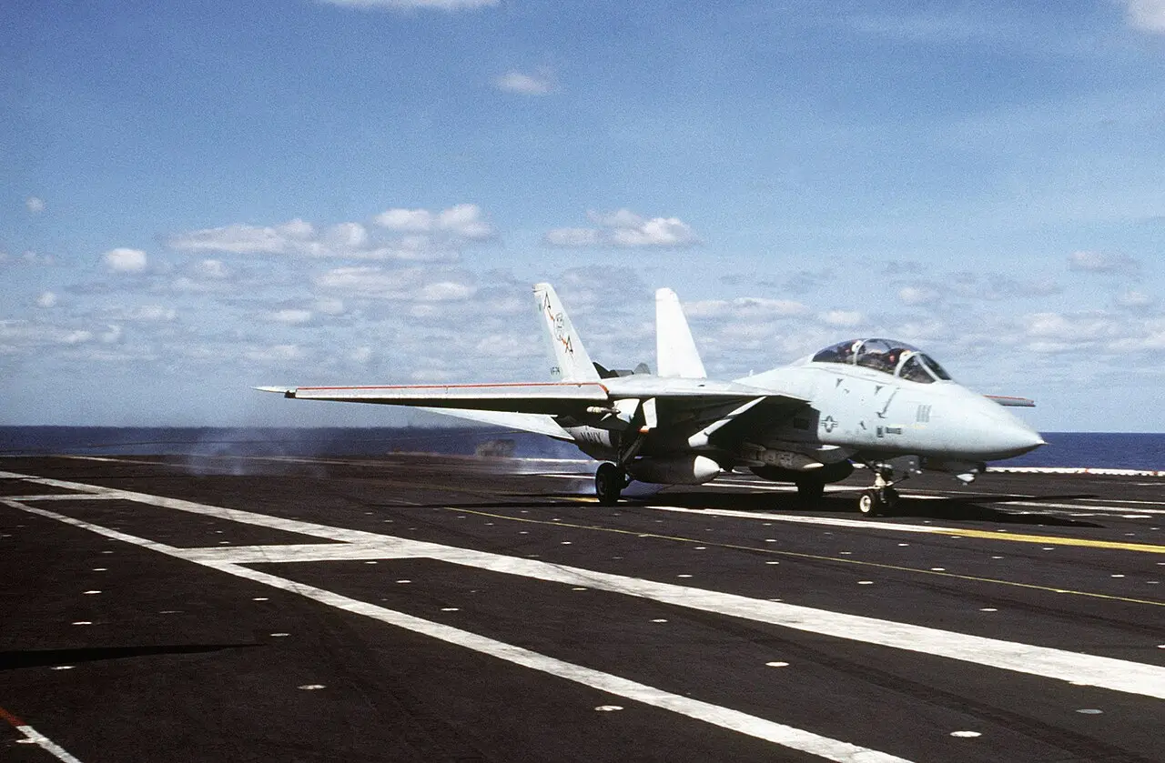 A U.S. Navy F-14A Tomcat fighter jet touching down on the flight deck of the aircraft carrier USS Saratoga in the Mediterranean Sea in 1985.
