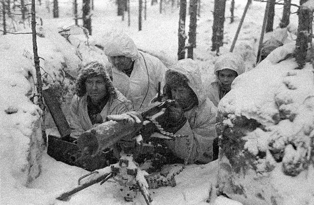 Finnish soldiers in white winter camouflage manning a Maxim machine gun in a snowy forest position during the Winter War (Finnish Defence Forces photograph).