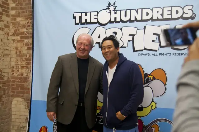 Garfield creator Jim Davis (left) poses with artist David Choe in front of a Garfield-themed display.