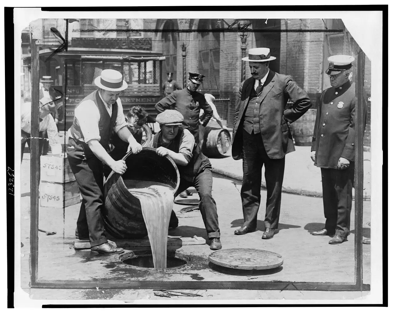 Prohibition agents pouring seized liquor into a New York City sewer while Deputy Police Commissioner John A. Leach watches, during the height of Prohibition.