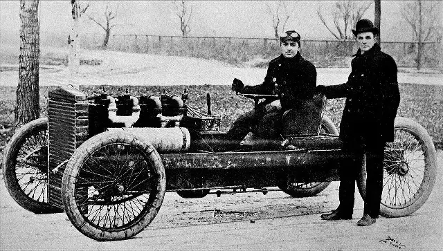 A 1902 photograph of racing driver Barney Oldfield seated in the Ford 999 racer with Henry Ford standing beside the car.