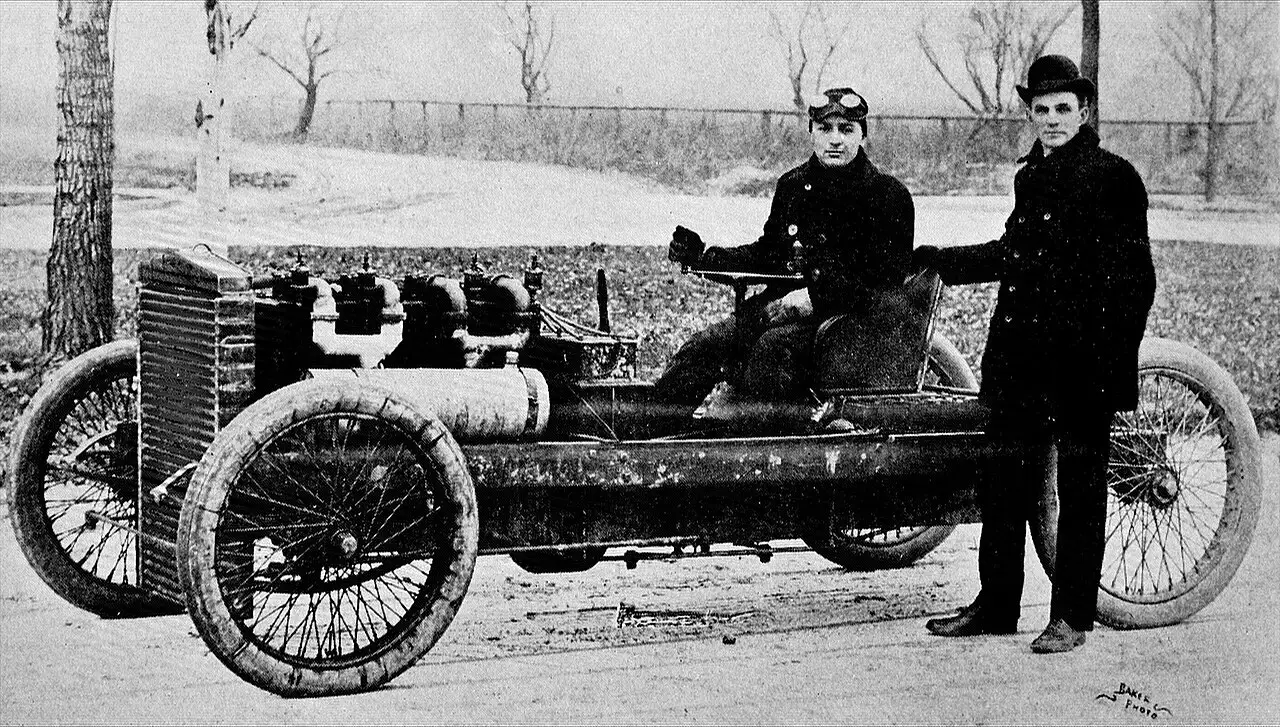 A 1902 photograph of racing driver Barney Oldfield seated in the Ford 999 racer with Henry Ford standing beside the car.
