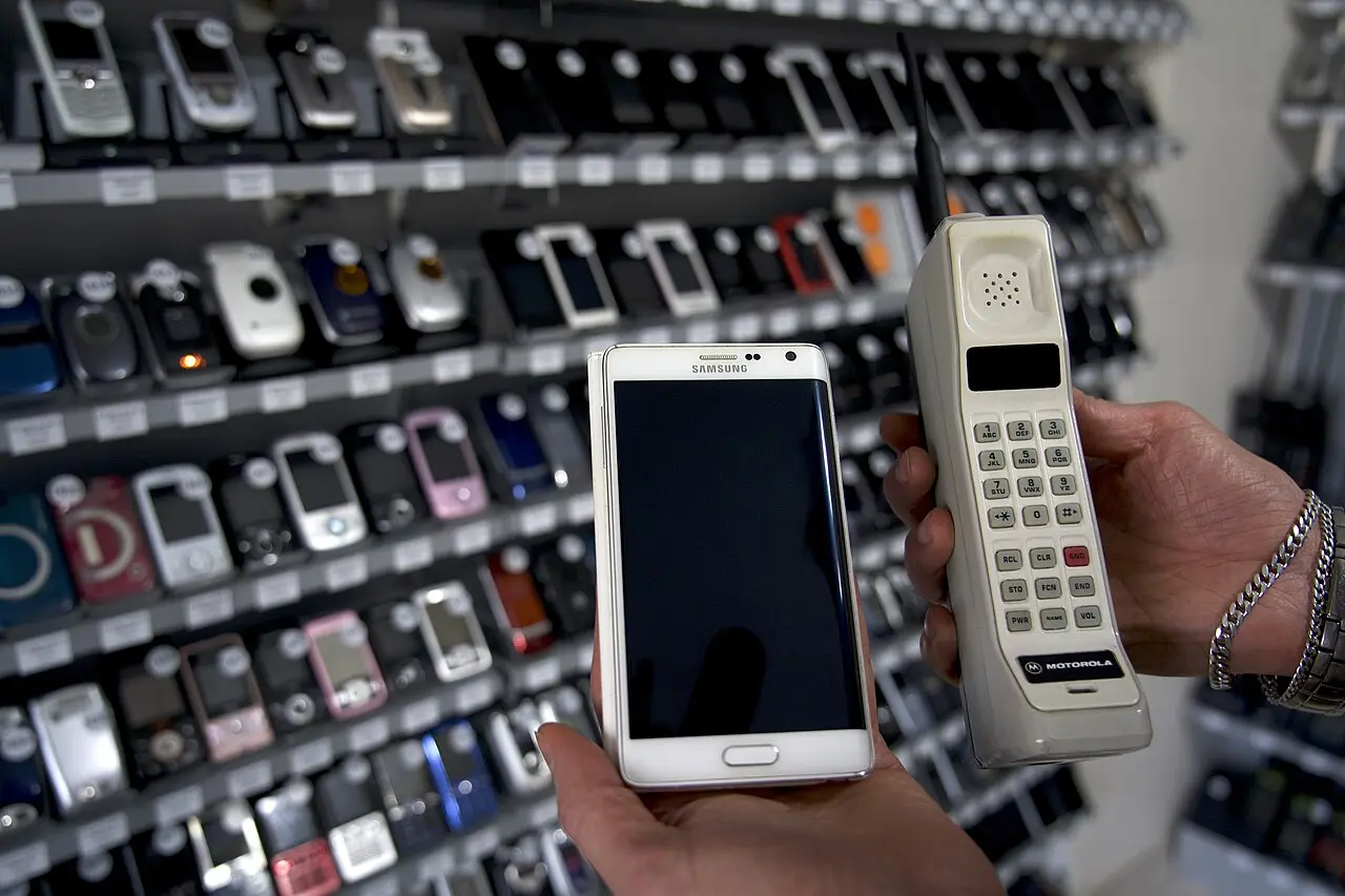 A Motorola DynaTAC brick phone held next to a modern Samsung smartphone for scale; illustrative.