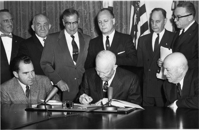 President Dwight D. Eisenhower signs the Alaska Statehood Act on July 7, 1958, surrounded by officials; the act set the stage for Alaska's formal admission as the 49th state on January 3, 1959.