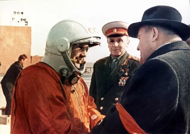 Yuri Gagarin in his orange spacesuit and white helmet, photographed with officials at the launch site shortly before his April 12, 1961 flight