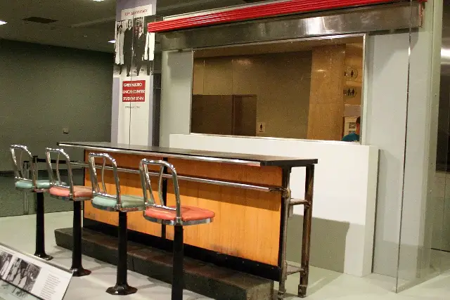 The preserved Greensboro Woolworth's lunch counter on display at the Smithsonian National Museum of American History, with a banner marking the February 1960 student sit-in.