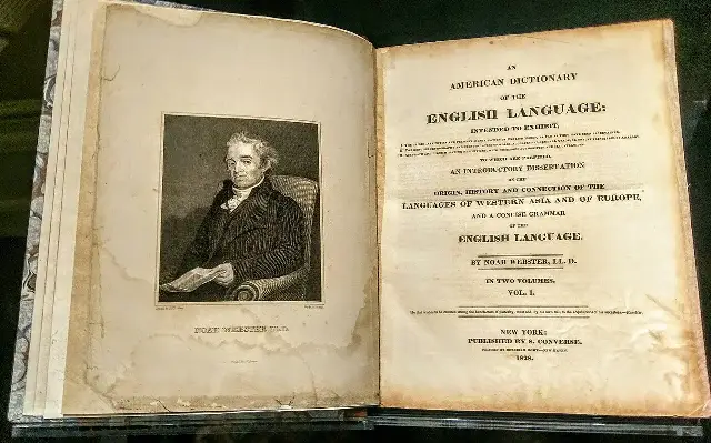 Open 1828 first edition of Noah Webster's An American Dictionary of the English Language, with an engraved portrait of Webster on the left page and the original title page on the right