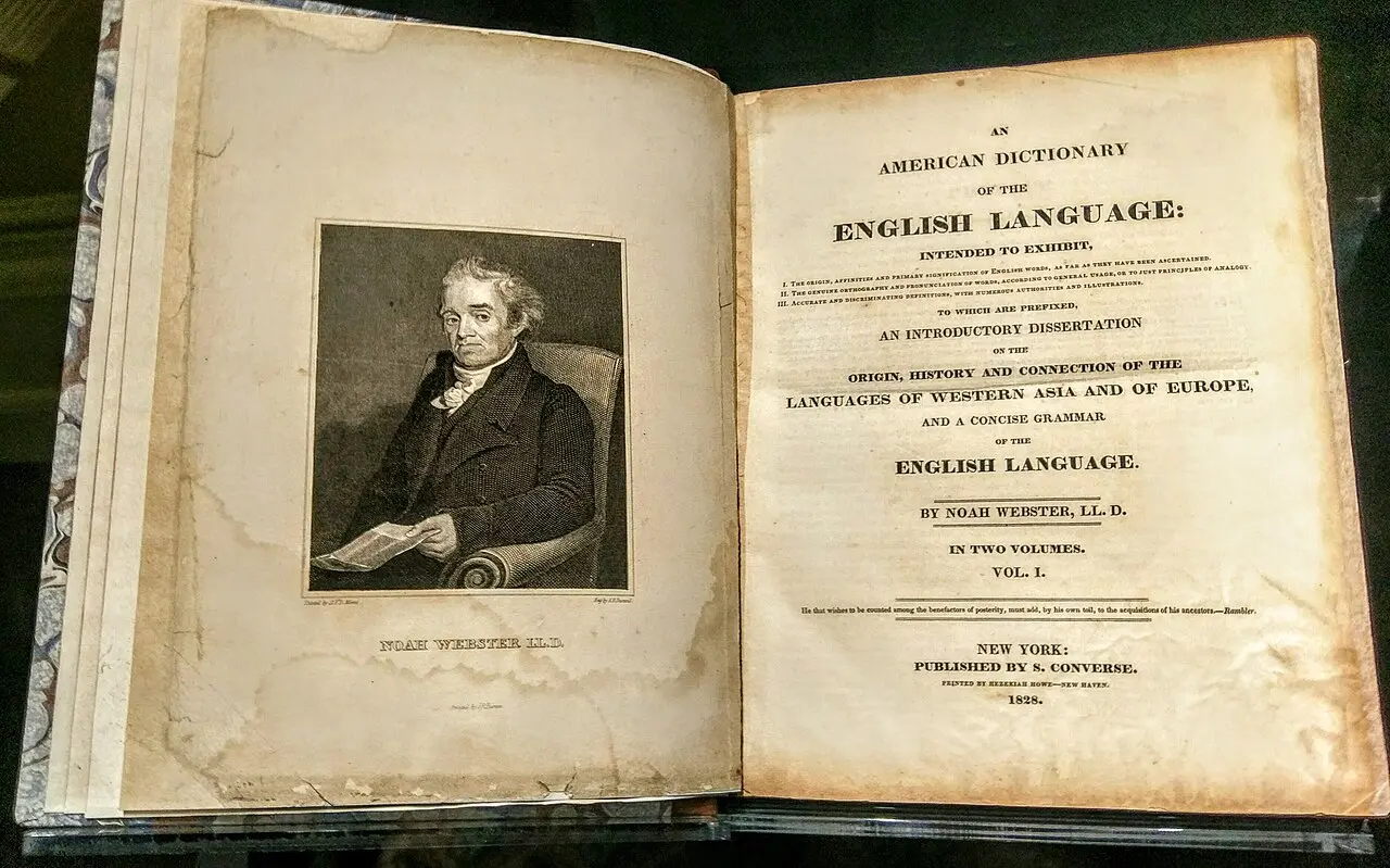 Open 1828 first edition of Noah Webster's An American Dictionary of the English Language, with an engraved portrait of Webster on the left page and the original title page on the right