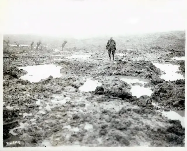 A lone soldier crossing the waterlogged, shell-torn mud of Passchendaele in 1917.