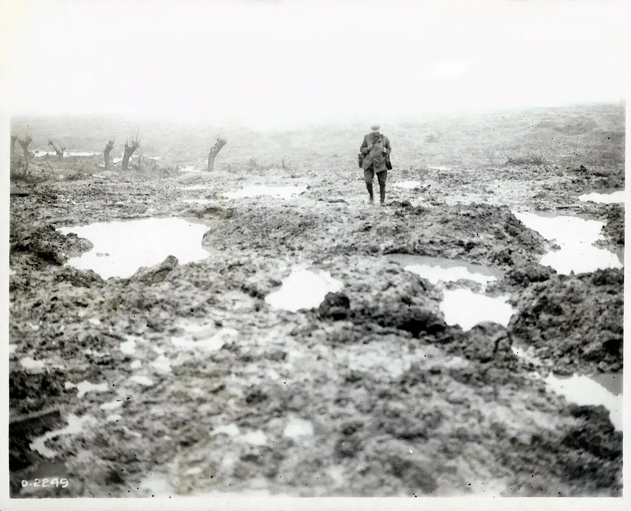 A lone soldier crossing the waterlogged, shell-torn mud of Passchendaele in 1917.